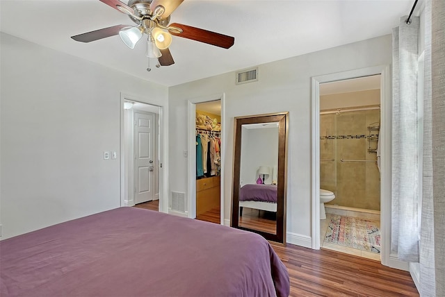 bedroom featuring dark hardwood / wood-style floors, a walk in closet, ceiling fan, ensuite bath, and a closet