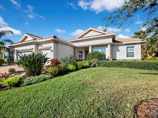 mediterranean / spanish house featuring a garage and a front lawn