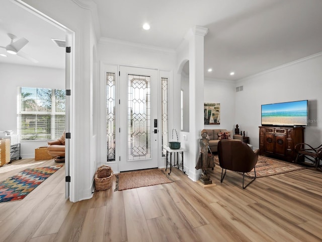 foyer with crown molding, light hardwood / wood-style flooring, and ornate columns