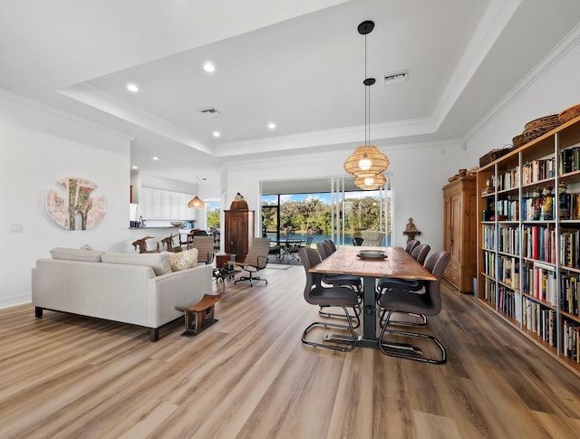 dining room featuring crown molding, light hardwood / wood-style floors, and a tray ceiling