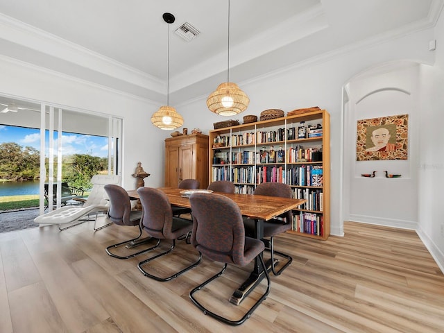 dining room with crown molding, a tray ceiling, and light hardwood / wood-style flooring