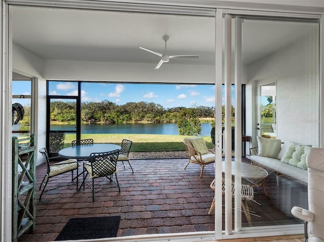 sunroom / solarium with a water view, ceiling fan, and a healthy amount of sunlight