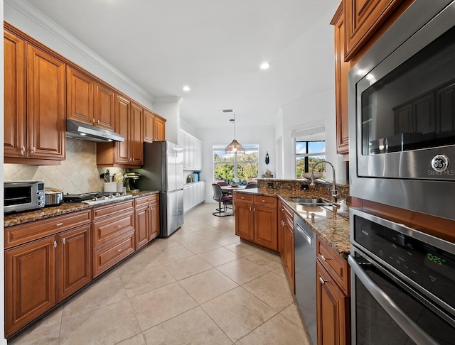 kitchen featuring pendant lighting, tasteful backsplash, sink, dark stone counters, and stainless steel appliances