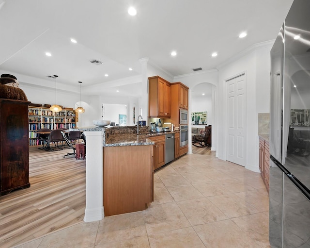 kitchen featuring decorative light fixtures, dark stone countertops, kitchen peninsula, stainless steel appliances, and crown molding