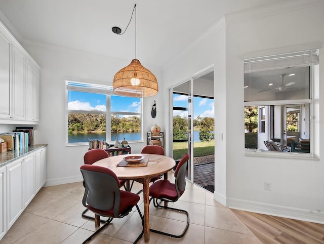 dining space featuring crown molding, a water view, and light tile patterned floors