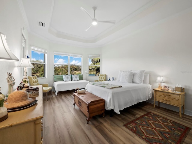 bedroom with a raised ceiling, hardwood / wood-style floors, and multiple windows