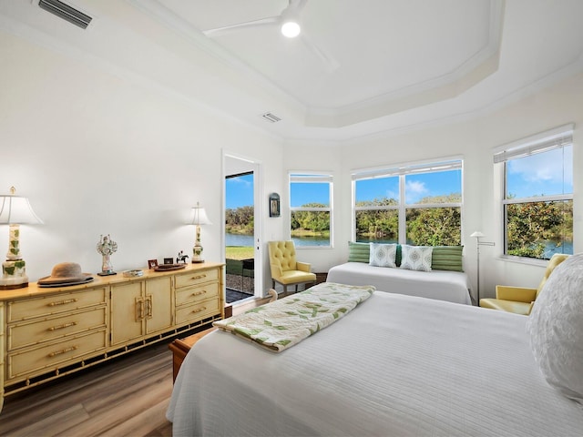 bedroom with dark hardwood / wood-style floors, ornamental molding, access to outside, ceiling fan, and a tray ceiling