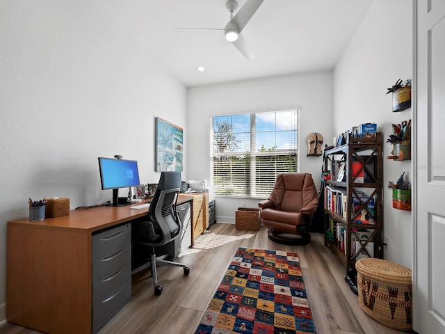 home office with light hardwood / wood-style flooring and ceiling fan