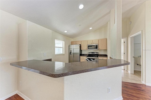 kitchen featuring hardwood / wood-style floors, lofted ceiling, kitchen peninsula, stainless steel appliances, and light brown cabinets