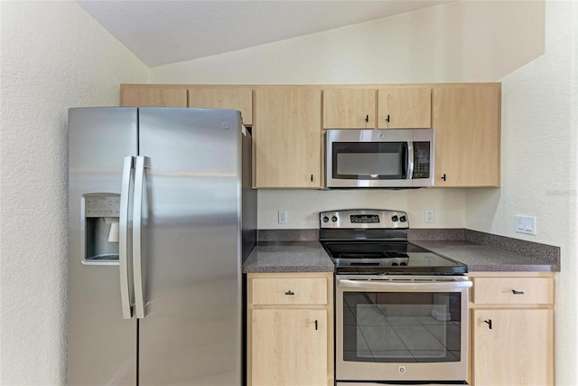 kitchen with vaulted ceiling, appliances with stainless steel finishes, and light brown cabinets