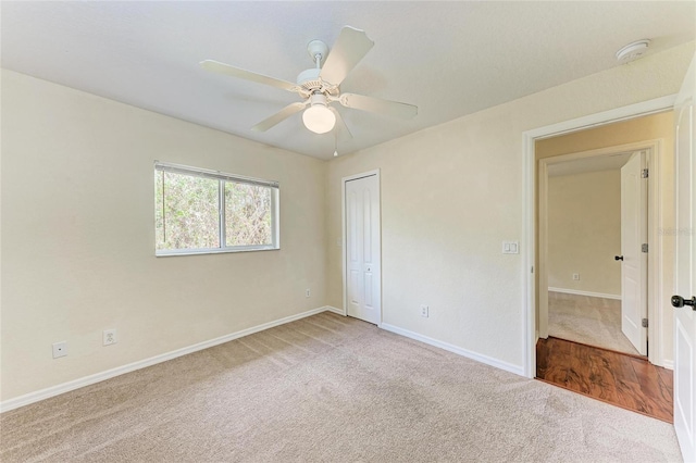 carpeted empty room featuring ceiling fan and a closet