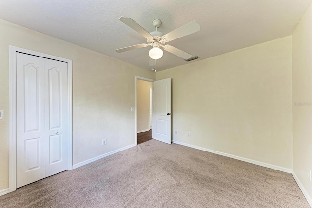 unfurnished bedroom featuring a textured ceiling, carpet floors, a closet, and ceiling fan