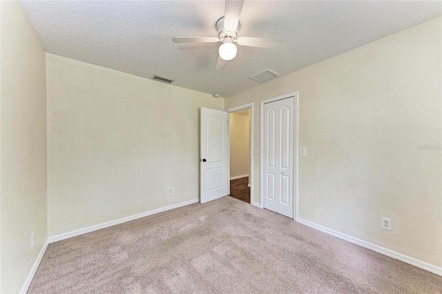 carpeted empty room featuring ceiling fan and a textured ceiling