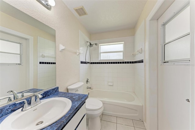 full bathroom featuring toilet, tiled shower / bath, a textured ceiling, vanity, and tile patterned flooring