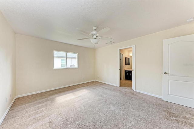 unfurnished room featuring ceiling fan, light colored carpet, and a textured ceiling