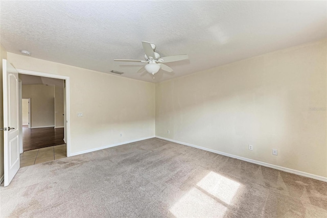 carpeted spare room featuring ceiling fan and a textured ceiling