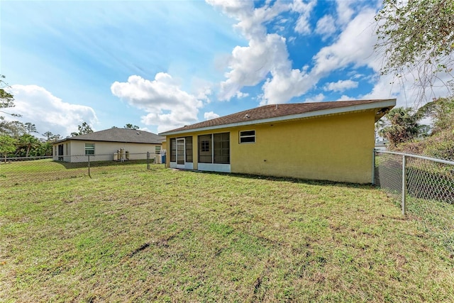 back of property with a sunroom and a lawn