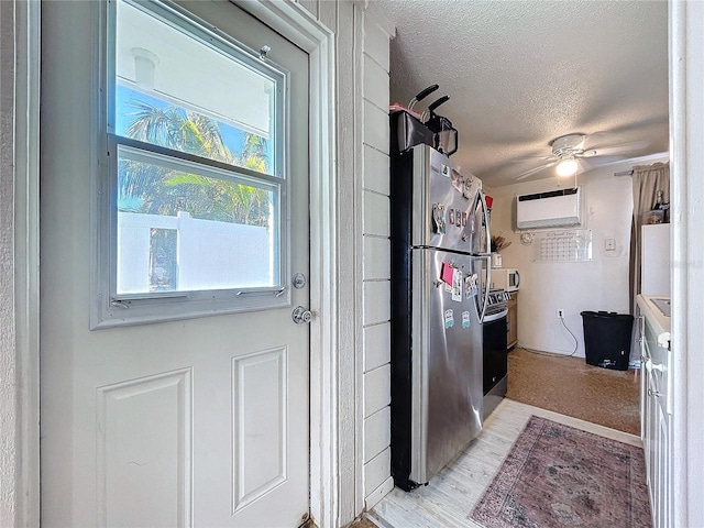 kitchen featuring a textured ceiling, ceiling fan, a wall mounted air conditioner, and freestanding refrigerator