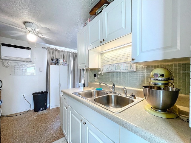 kitchen featuring tasteful backsplash, light countertops, white cabinetry, a sink, and a textured ceiling