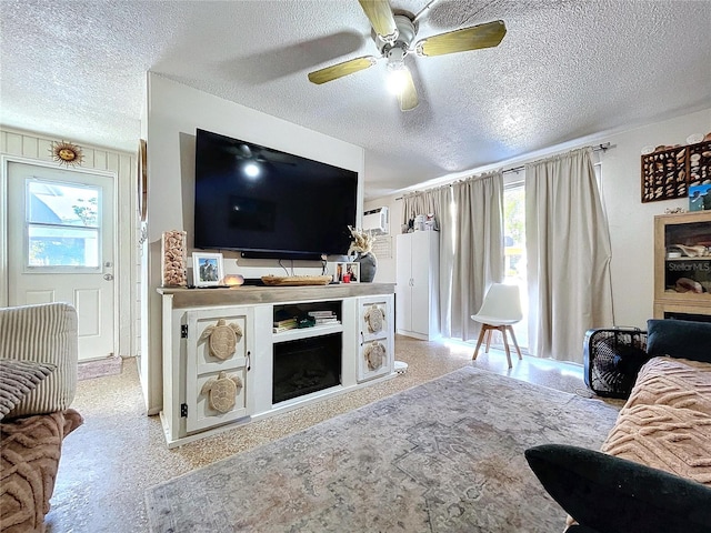 living room with a ceiling fan, a healthy amount of sunlight, a fireplace, and a textured ceiling