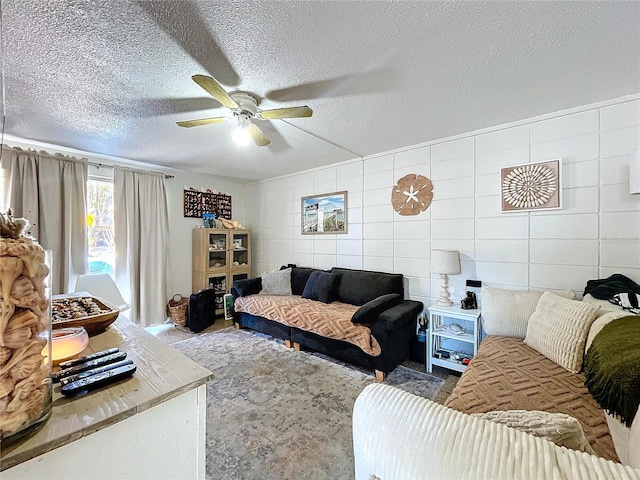 carpeted living area featuring a ceiling fan, tile walls, and a textured ceiling