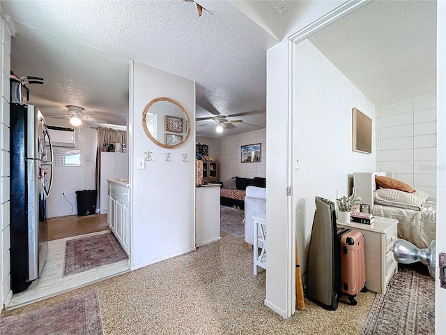 hall with tile walls and a textured ceiling