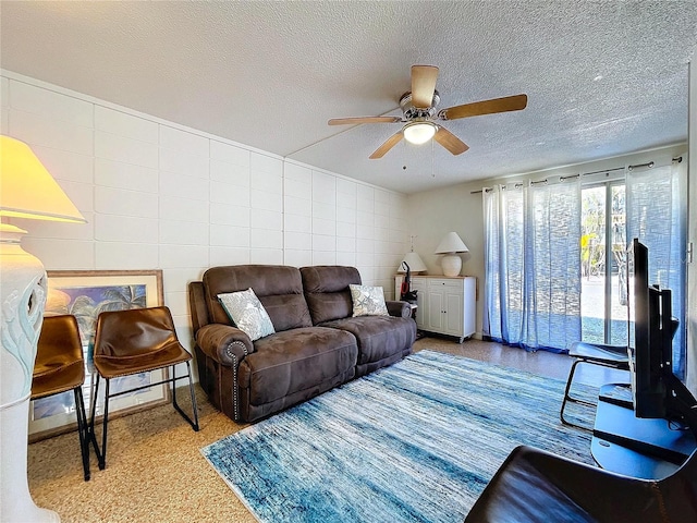 living area featuring tile walls, ceiling fan, and a textured ceiling