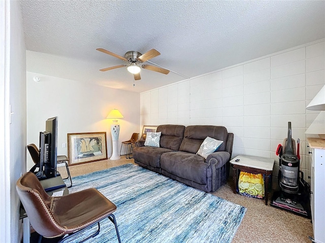 carpeted living room with a textured ceiling, ceiling fan, and tile walls