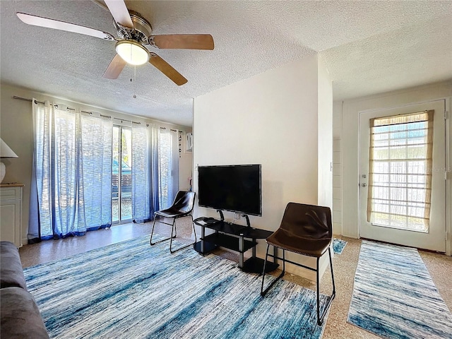 living room featuring ceiling fan and a textured ceiling