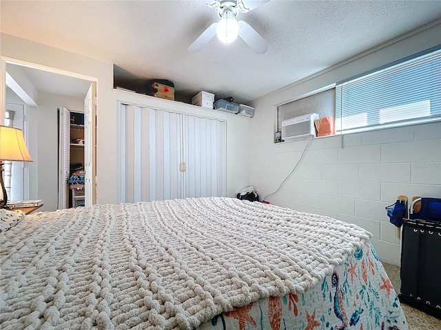 bedroom featuring concrete block wall, a ceiling fan, and a textured ceiling