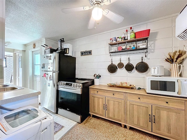 kitchen with a textured ceiling, light brown cabinets, stainless steel appliances, separate washer and dryer, and a sink