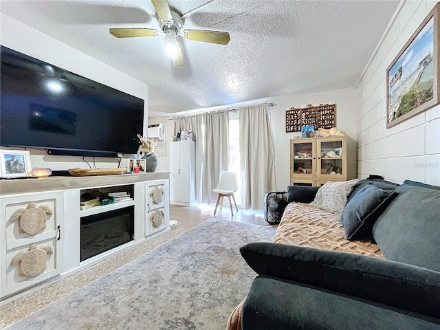 living room featuring a textured ceiling, ceiling fan, and a glass covered fireplace