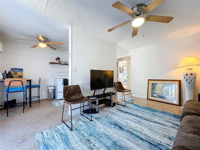 living room featuring carpet floors, a ceiling fan, tile walls, and a textured ceiling