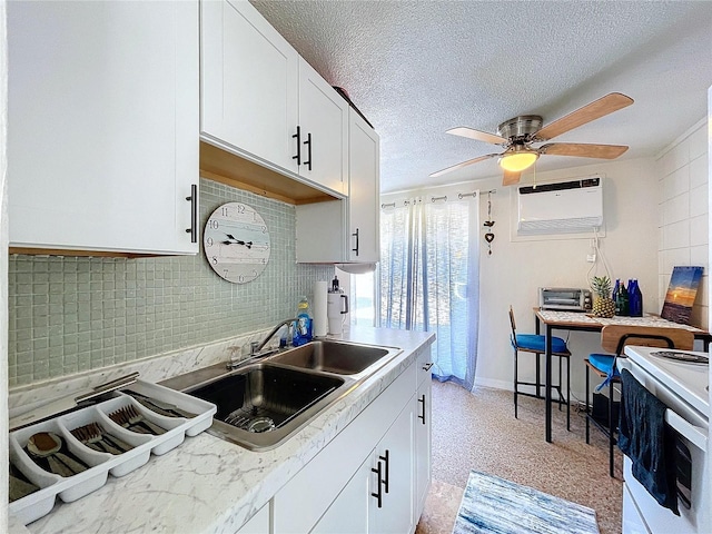 kitchen featuring light countertops, an AC wall unit, white cabinets, a sink, and a textured ceiling