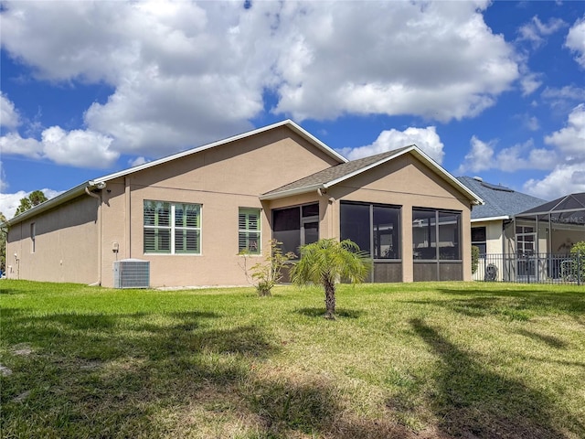 rear view of property featuring a yard, a sunroom, and central AC