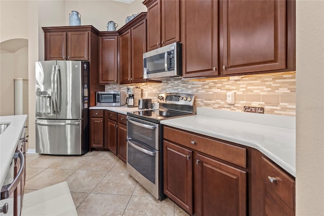 kitchen featuring appliances with stainless steel finishes, light tile patterned flooring, and tasteful backsplash