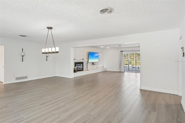 unfurnished living room with a fireplace, hardwood / wood-style floors, and a textured ceiling