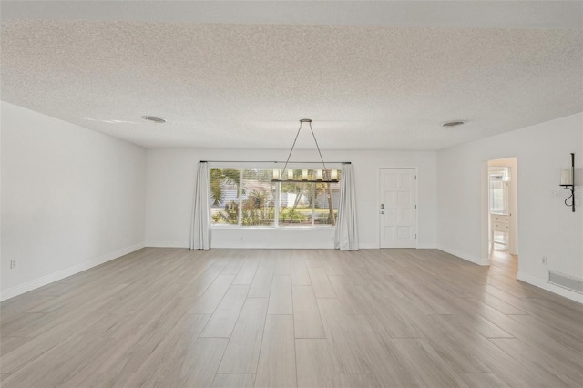 interior space with a textured ceiling, a chandelier, and light hardwood / wood-style flooring