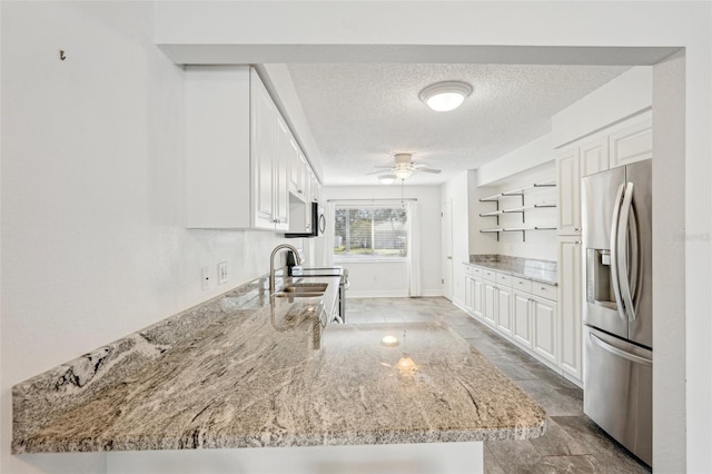 kitchen featuring white cabinetry, light stone countertops, and stainless steel fridge