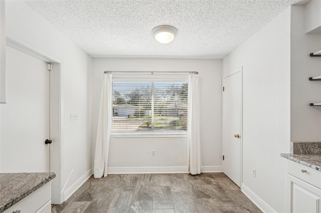 unfurnished dining area with a textured ceiling