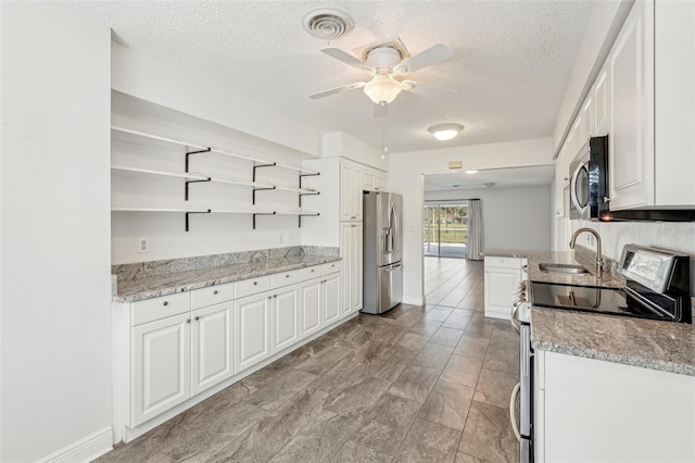 kitchen featuring appliances with stainless steel finishes, light stone countertops, sink, and white cabinets