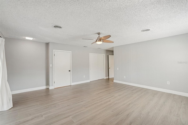 spare room with a textured ceiling, ceiling fan, and light wood-type flooring