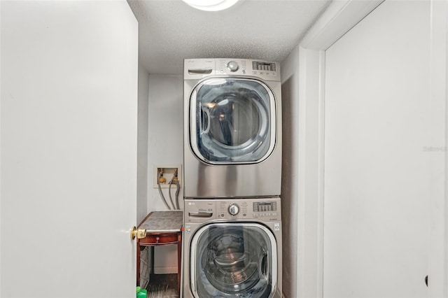 clothes washing area with stacked washer / drying machine and a textured ceiling