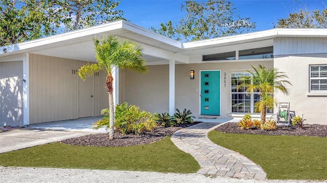 property entrance with a lawn and a carport