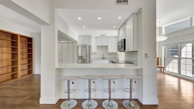 kitchen with sink, white cabinetry, stainless steel appliances, dark hardwood / wood-style flooring, and kitchen peninsula