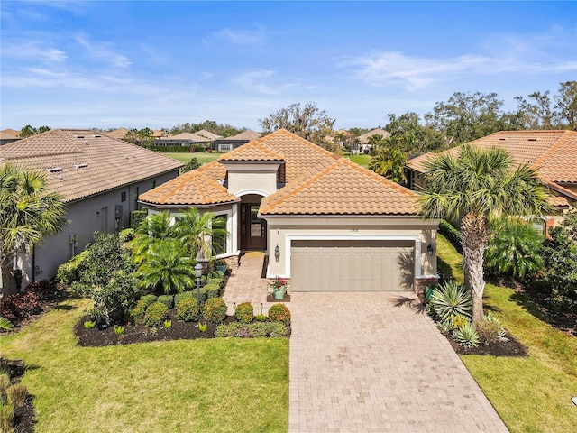 mediterranean / spanish-style home featuring a garage, a tile roof, decorative driveway, stucco siding, and a front yard