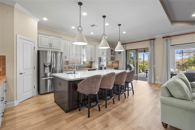 kitchen featuring stainless steel appliances, a breakfast bar, visible vents, open floor plan, and light wood-type flooring