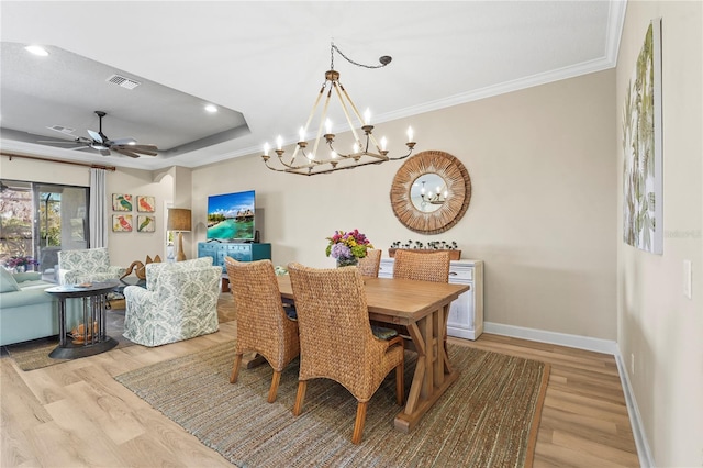 dining area with light wood finished floors, baseboards, visible vents, and a tray ceiling