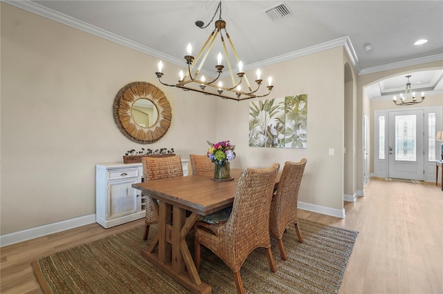 dining room with arched walkways, a notable chandelier, visible vents, light wood-type flooring, and crown molding