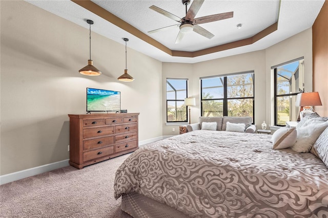 carpeted bedroom featuring a ceiling fan, a textured ceiling, baseboards, and a tray ceiling